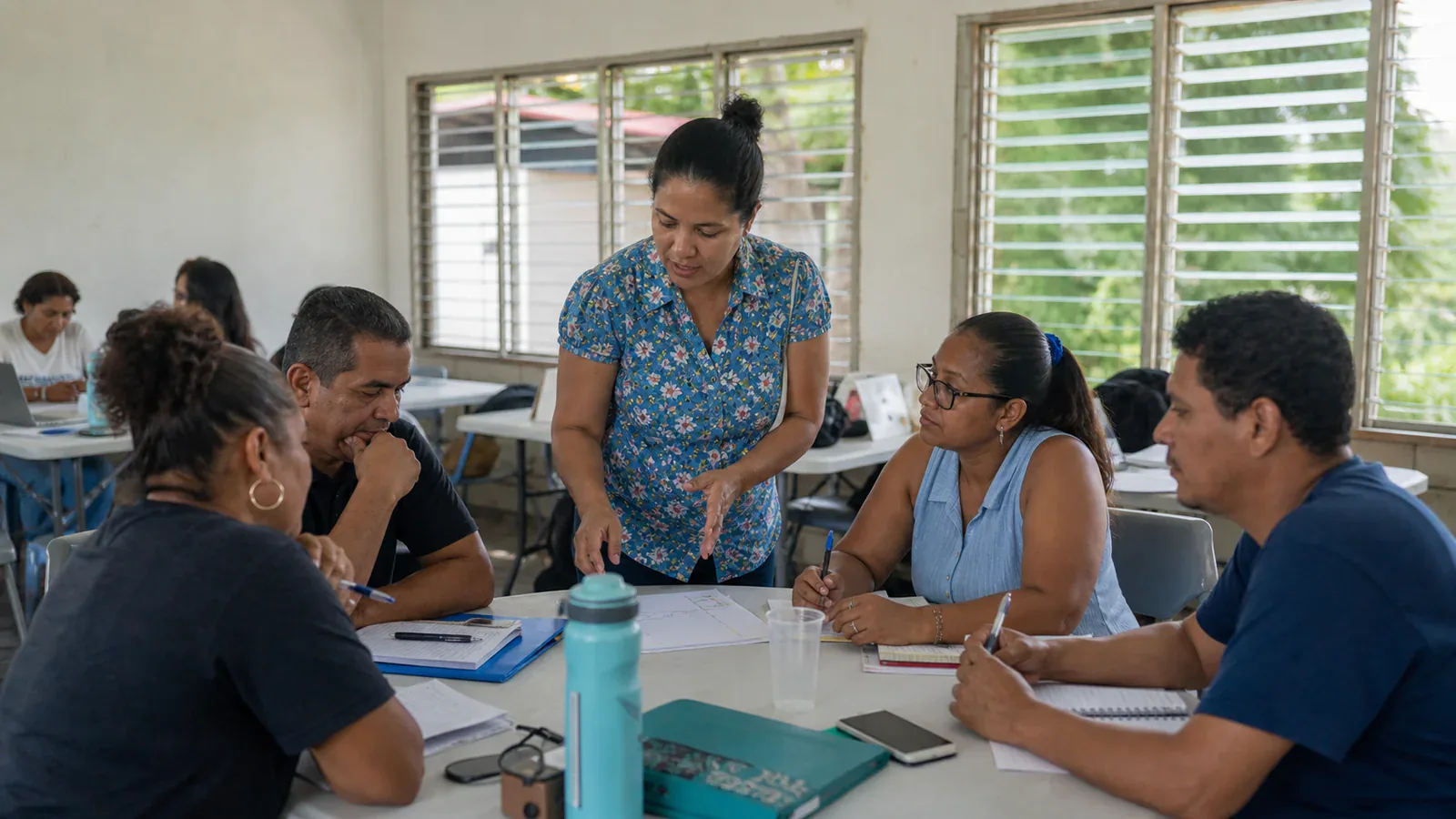 Una facilitadora guía a personas adultas en un ejercicio práctico dentro de un salón de capacitación comunitaria.