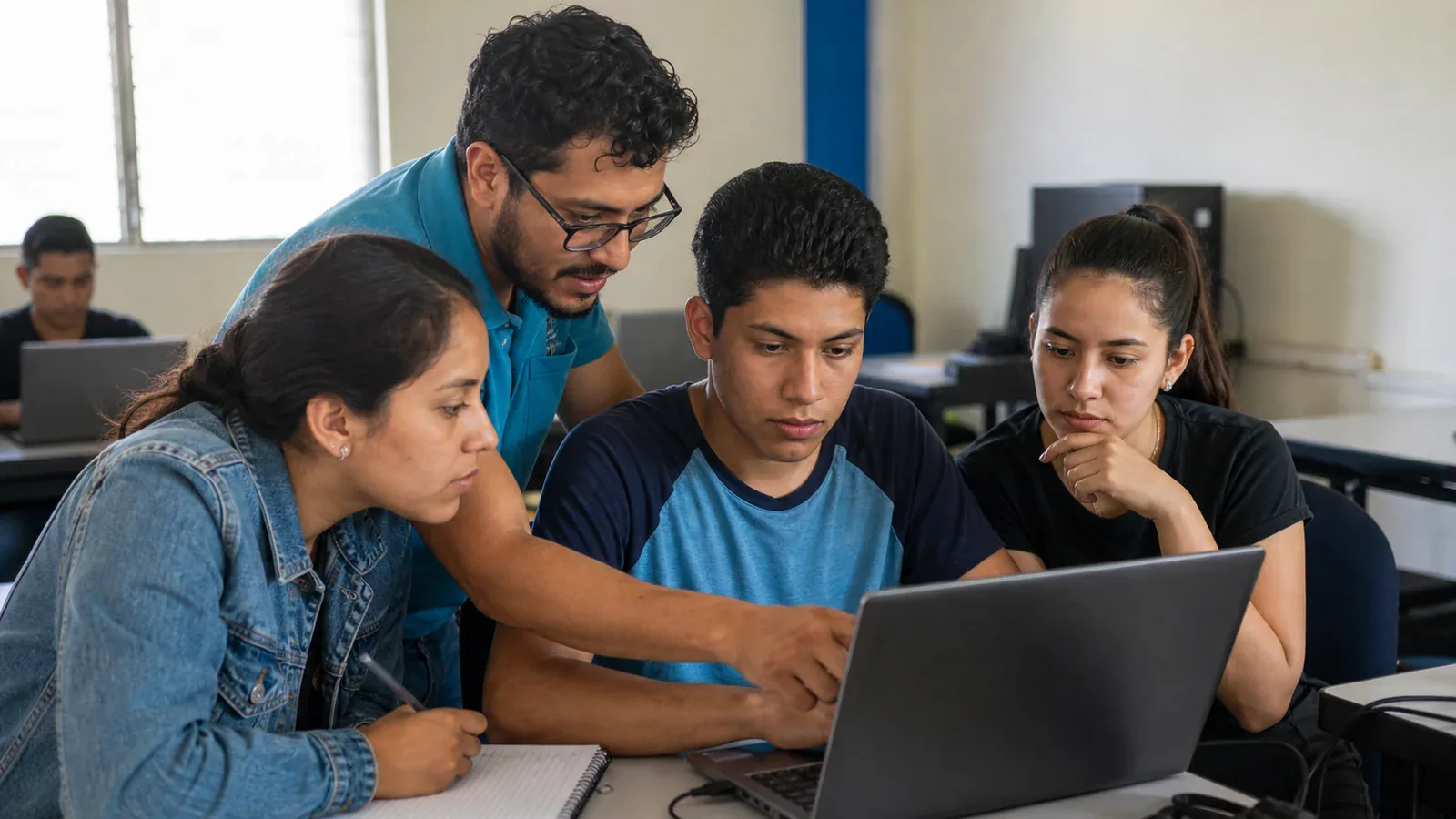 Un mentor y tres estudiantes revisan juntos un ejercicio de programación en una laptop.