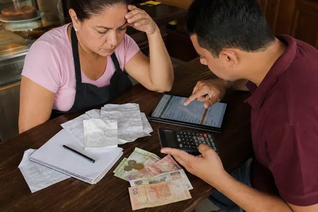 Cafe owner reviews receipts and cash flow with an accountant.