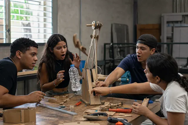 Team tests and adjusts a mechanism built from cardboard.