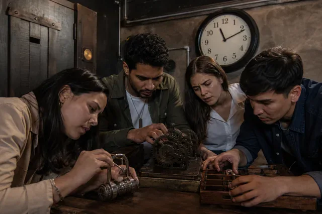 Coworkers solve locks and gears inside an escape room.