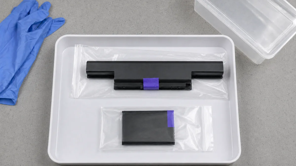 Baterías de litio de laptop y celular con terminales aislados, guardadas por separado para reciclaje seguro.